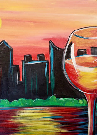 Canvas painting of a fun cityscape with a sunset sky and the sun bright in the sky but setting. Lots of oranges and yellows and reds. The skyline itself is black. There is a large wine glass in foreground with the wine reflecting the oranges and reds and yellows.