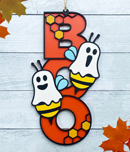 BOO wooden door sign featuring the letters B O O in a vertical format with various Halloween images pictured on top of the BOO. This one features two bumble bees dressed as ghosts. 