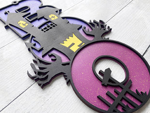 BOO wooden door sign featuring the letters B O O in a vertical format with various Halloween images pictured on top of the BOO. This one features a Haunted House. 