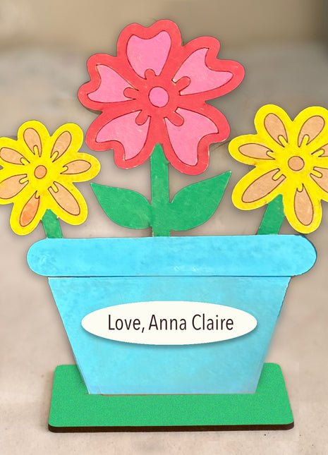 Wooden shelf sitter flower pot with three colorful flowers. 