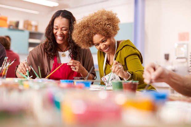 Two ladies laughing and chatting as they paint