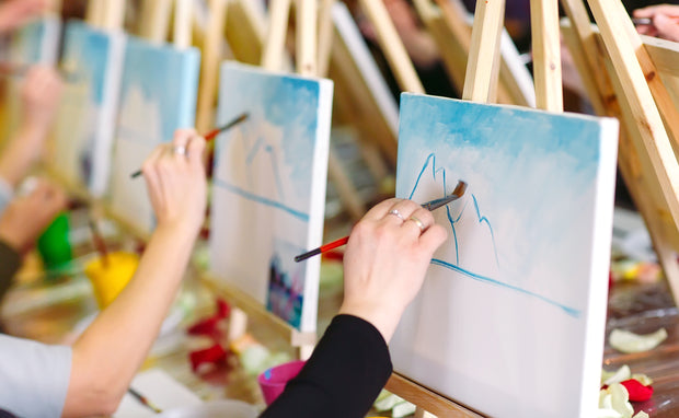A picture of people painting canvases on easels